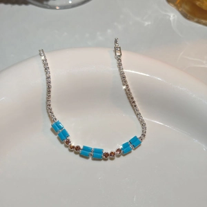 Macro shot of silver bracelet with blue gemstones and brown cubic zirconia on ceramic
