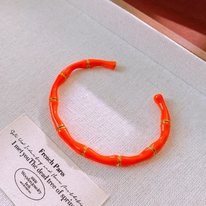 Primo piano dettagliato del bracciale a bambù in smalto arancione vivace con distanziatori dorati