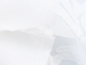Close-up of elegant white lace embroidery and fine stitching on a halter maxi dress