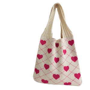 Minimalist beige knitted tote bag with pink heart pattern on a clean white background