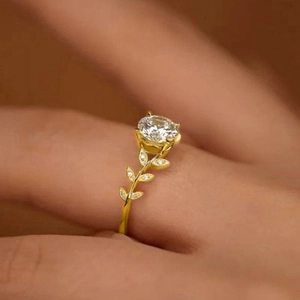 Macro detail of a gold leaf ring featuring a brilliant round center stone and diamond petals