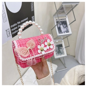 Detail of pink tweed girl's handbag featuring pearl handle, mesh bow and daisy accents