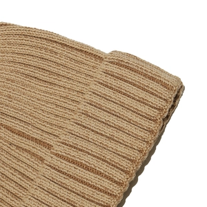 Detailed close-up of camel ribbed knit texture and thick stitching on a winter beanie