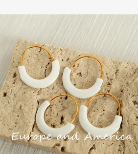 Detailed macro view of white enamel U-shaped earrings on textured stone surface