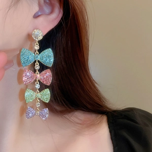 Detail of long tassel earrings featuring four colorful rhinestone bows on gold metal