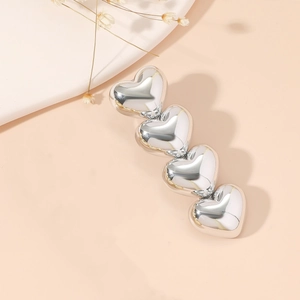 Elegant four-heart silver alloy hair clip with polished finish on beige background