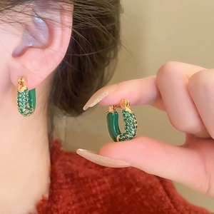 Vintage green enamel U-shaped earrings with gold zircon accents on a model's ear