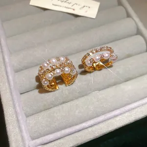 Gold multi-layer open earrings with white pearls and sparkling zircons on velvet
