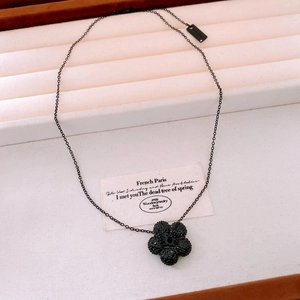Detail of a black floral pendant necklace with crystal accents in a luxury jewelry box