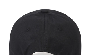 Detail view of black cotton baseball cap showing top button and embroidered eyelets