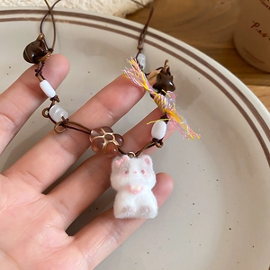Detail of handmade necklace with white flocked cat pendant and brown woven cord