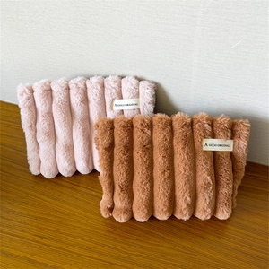 Detail of pink and camel plush cosmetic bags with soft wavy texture and fabric labels