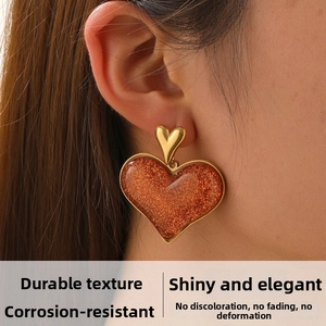 Macro shot of gold-plated stainless steel earrings with sparkling brown glitter heart pendant