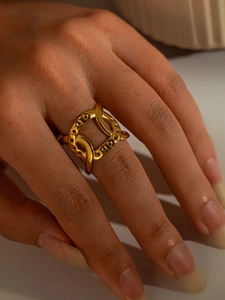 Detail of golden geometric open ring with embossed dots on a minimalist band
