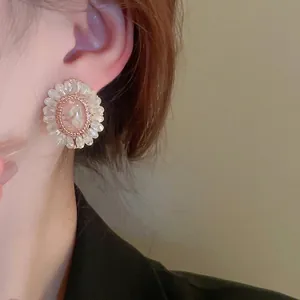 Elegant floral stud earrings with pink crystal center and clear beaded petals on model
