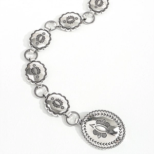 Detailed shot of vintage silver metal waist chain with intricate floral carvings and charms