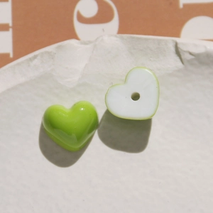 Detailed view of heart-shaped resin beads in grass green and white for DIY crafts
