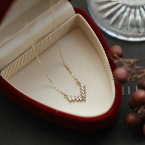 Elegant gold V-shaped necklace with baguette cubic zirconia in a red heart jewelry box