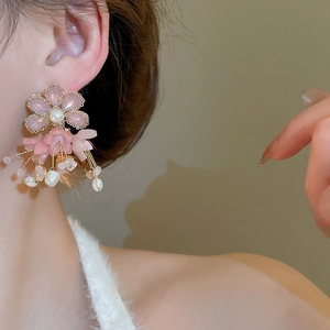 Detail of floral tassel earrings with pink petals and pearls worn on ear for vacation look