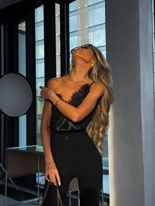 Détail du caraco en satin noir avec dentelle délicate au col en V et texture soyeuse