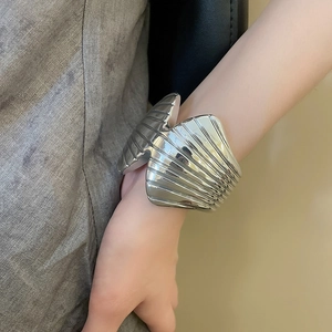 Detail of silver pleated cuff bracelet featuring vertical textured metal surface on wrist