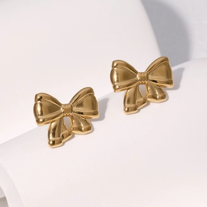 Boucles d'oreilles nœud dorées en acier inoxydable poli sur un support blanc minimaliste