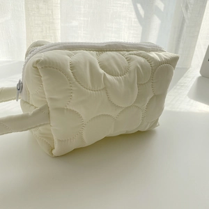 Close-up of cream white quilted flower makeup bag with soft padded texture and resin zipper