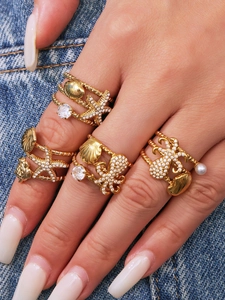 Detailed close-up of four gold marine rings featuring starfish, shells, and pearls