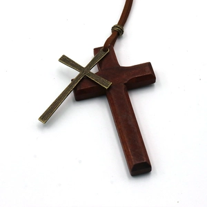 Detail eines vintage Doppelkreuz-Anhängers aus Holz und Bronze am braunen Lederband