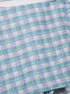 Close-up of blue and purple textured tweed fabric with intricate woven checkered pattern
