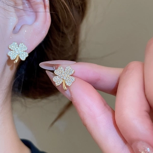 Macro shot of sparkling gold four-leaf clover earrings with full pavé cubic zirconia