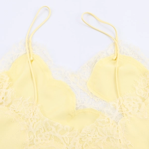 Detailed flat lay of pale yellow satin camisole with delicate eyelash lace trim on white base