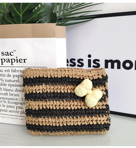 Detail of striped crochet straw envelope bag with bow accent and top zipper closure