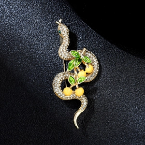 Macro detail of snake brooch with clear rhinestones, green enamel leaves and yellow berries