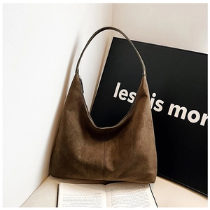Detail of a vintage dark brown suede tote bag on a minimalist table with a book