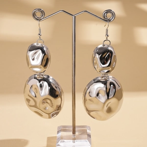 Detailed close-up of silver irregular geometric drop earrings with textured hammered finish