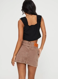 Détail du dos de la mini-jupe en jean avec patch en cuir et crop top plissé élégant