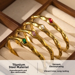 Detailed macro of gold C-shaped titanium steel bangles with colorful zircon gemstones