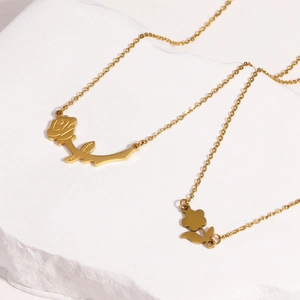 Detailed view of a romantic golden rose pendant necklace on a white stone background