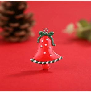Detailed close-up of a red resin Christmas bell pendant with a green bow and white dots