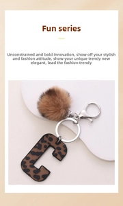 Close-up of leopard print letter C keychain with a brown fluffy pompom on a display stand