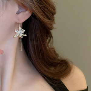 Close-up of silver iris flower drop earrings worn by a model for an elegant style