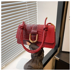 Close-up of red crocodile texture bag with woven handle and gold metal hardware