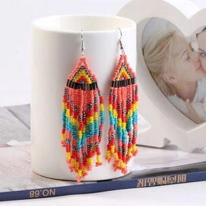 Detail of colorful bohemian seed bead tassel earrings hanging on a white decorative stand