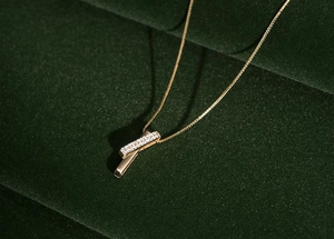 Close-up of geometric gold necklace pendant with zircon stones on green velvet