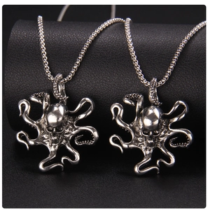Detail of silver skull octopus pendants on black textured leather in punk hip hop style