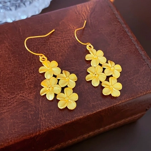 Macro view of vintage matte gold flower earrings with pearls on brown leather jewelry box