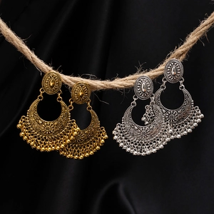 Detail of vintage bohemian tassel earrings with floral engravings on black silk background