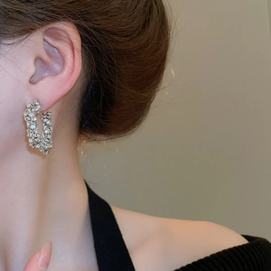 Detail of silver star earrings featuring dense zircon crystals on rectangular hoops