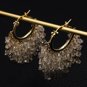 Elegant gold hoop earrings with sparkling crystal tassels on dark luxury background